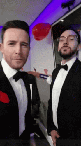 Two Men in Tuxedos and Bow Ties With Red Heart