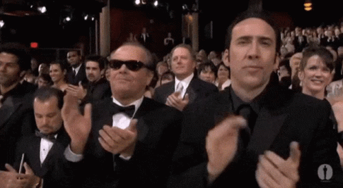 Two Men In Tuxedos And Sunglasses Are Clapping In A Crowd Of People . GIF