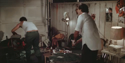 Two Men In White Tank Tops Are Standing In A Room GIF