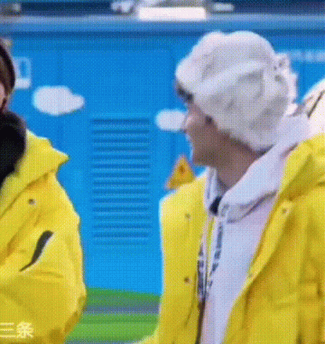 Two Men in Yellow Jackets and White Hats Talking