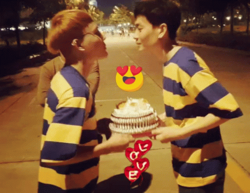 Two Men Kissing While Holding A Cake With Hearts And The Letter E GIF