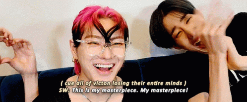 Two Men Laughing on Couch With Pink and Black Hair