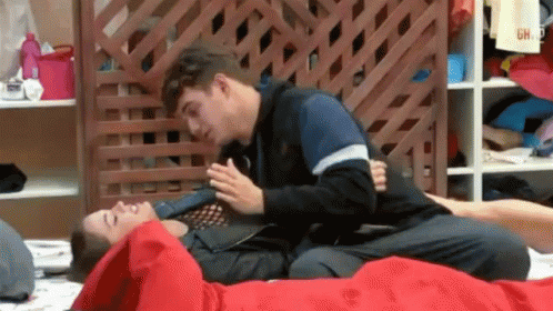 Two Men Laying on Top of Each Other on Bed with Wooden Fence