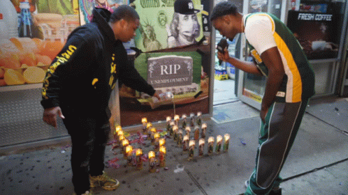 Two Men Lighting Candles at RIP Sign