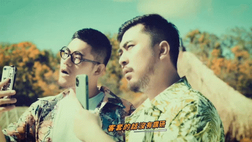 Two Men Looking at Cell Phones With Chinese Writing