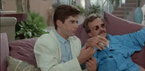 Two Men on Couch Talking One Smoking