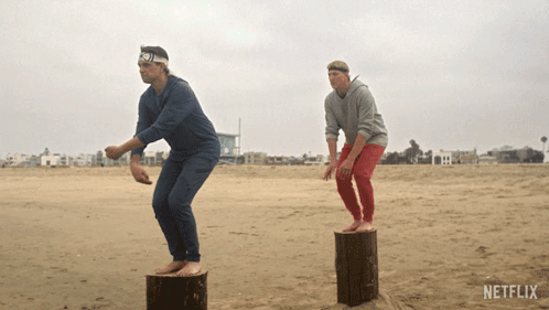 Two Men On Logs At Beach With Netflix GIF