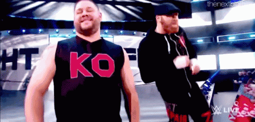 Two Men on Stage One Wearing Ko Shirt