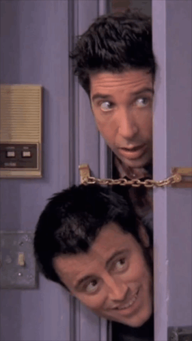 Two Men Peeking Out Of A Purple Door With A Chain Around Them GIF