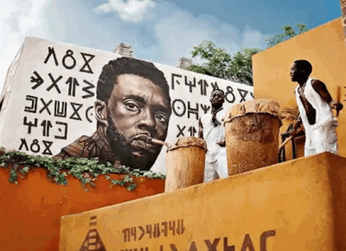 Two Men Playing Drums In Front Of A Mural Of A Man With A Cigar GIF