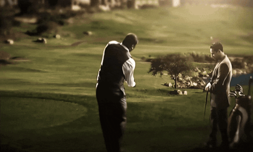 Two Men Playing Golf On A Lush Green Course GIF