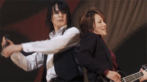 Two Men Playing Guitars White Shirt and Black Vest