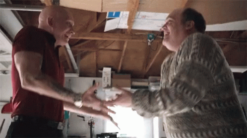 Two Men Shaking Hands in Garage One With Tattoo