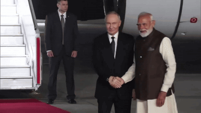 Two Men Shaking Hands On Red Carpet Near Plane GIF