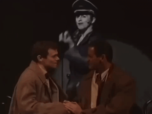 Two Men Shaking Hands With Man in Military Hat