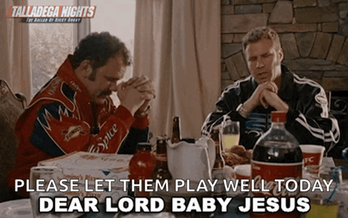Two Men Sit At A Table With A Sign That Says Talladega Nights GIF
