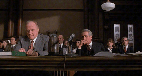 two men sitting at a table in a courtroom with the words objection behind them