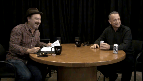 Two Men Sitting At A Table With A Can Of Bud Light GIF