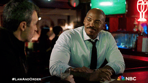 Two Men Sitting at Bar with NBC Logo