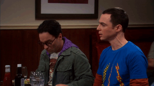 Two Men Sitting at Table With Ketchup and Water
