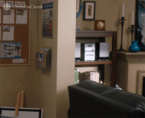 Two Men Sitting at Table With Schitt's Creek Sign