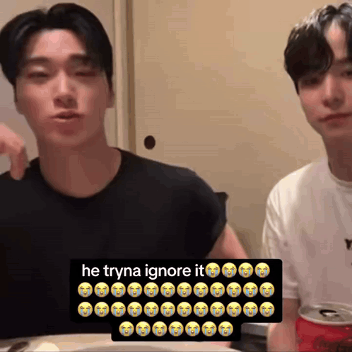 Two Men Sitting at Table With Soda Sign Saying He Tryna Ignore It