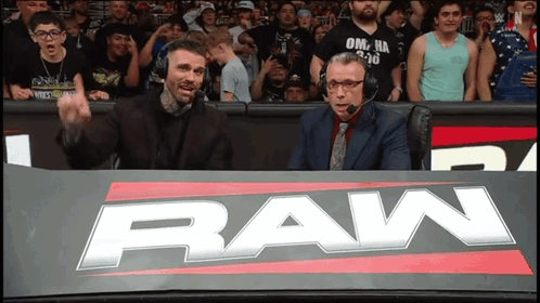 Two Men Sitting Behind Raw Sign GIF