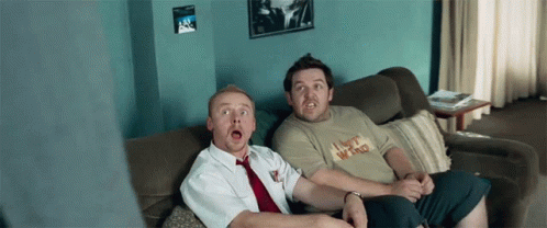 Two Men Sitting On A Couch One Of Whom Is Wearing A Shirt That Says I Bet Who GIF
