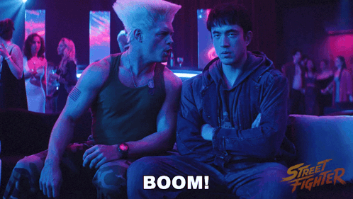 Two Men Sitting On A Couch With The Word Boom Written On The Bottom GIF