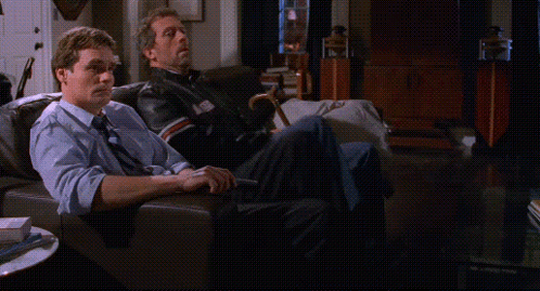 Two Men Sitting On A Couch With Their Feet Up GIF