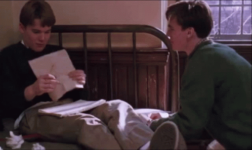 Two Men Sitting On Bed Looking At Papers GIF