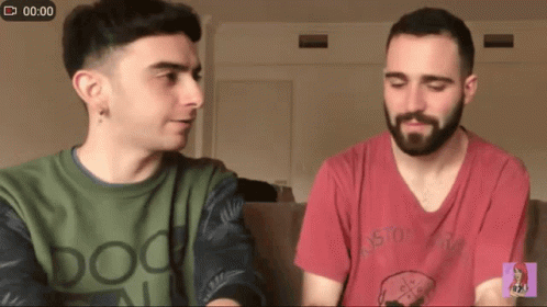 Two Men Sitting on Couch with Doo Shirt