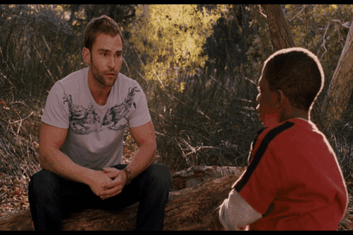 Two Men Sitting On Log Talking In Woods GIF