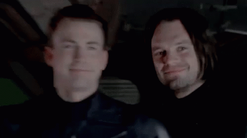 Two Men Smiling In Dark Room GIF
