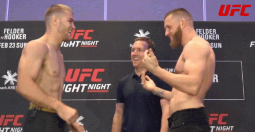 Two Men Standing by UFC Light Night Sign