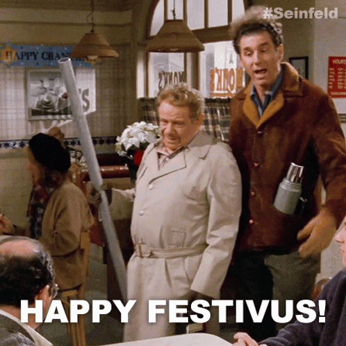 Two Men Standing In A Restaurant With The Words Happy Festivus On The Bottom GIF