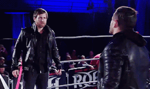 Two Men Standing In A Wrestling Ring With A Sign That Says Rock GIF