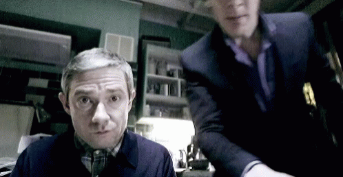 Two Men Standing in Dark Room One Looking at Camera