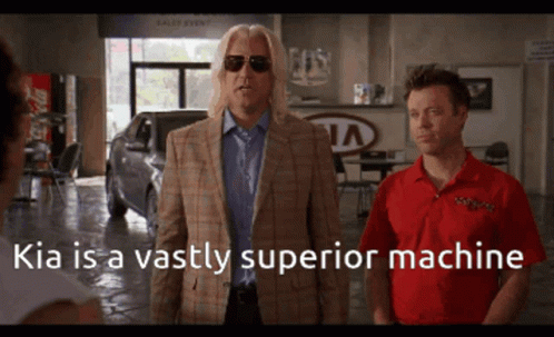 Two Men Standing In Front Of A Kia Dealership With The Caption Kia Is A Vastly Superior Machine GIF