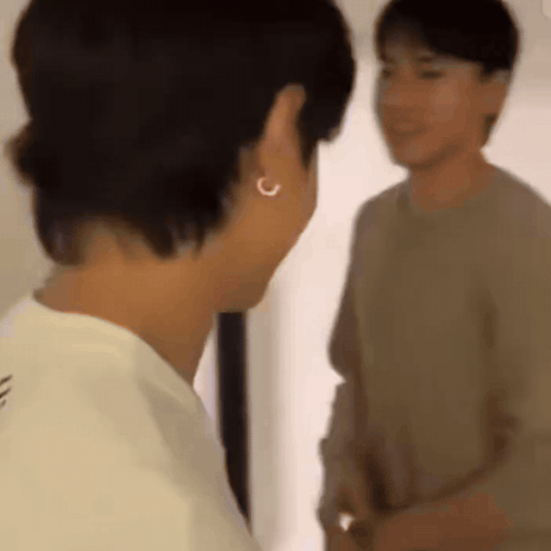 Two Men Standing in Front of a Mirror, One Wearing Earrings