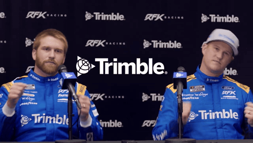 two men standing in front of a trimble banner