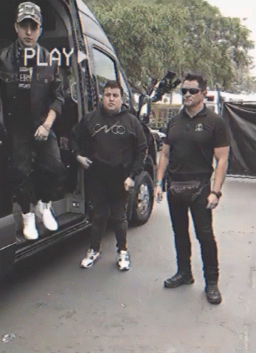 Two Men Standing In Front Of A Van With The Word Play On The Screen GIF