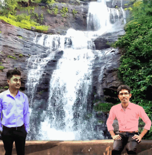 Two Men Standing In Front Of A Waterfall With One Wearing A Pink Shirt GIF