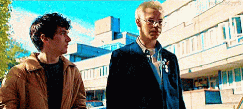 Two Men Standing In Front Of Building GIF