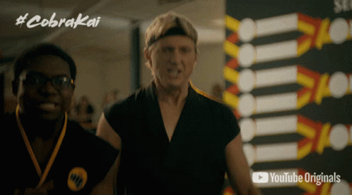 Two Men Standing in Front of Cobra Kai Sign