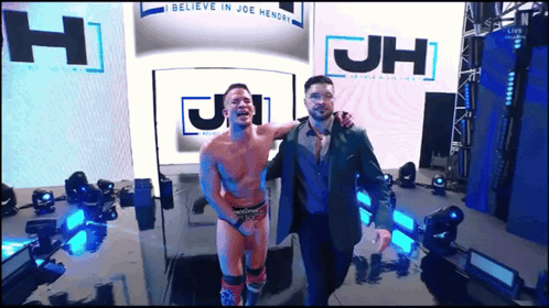 Two Men Standing In Front Of JH Sign GIF