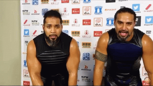 Two Men Standing In Front Of NPW World Wall GIF
