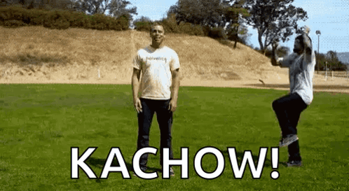Two Men Standing in Grass Field with Kachow