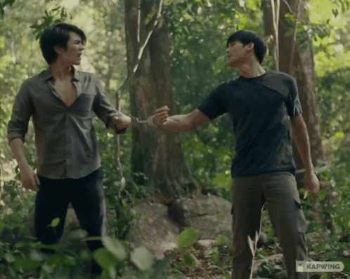 Two Men Standing In The Woods With Kapwing Written On The Bottom Left GIF