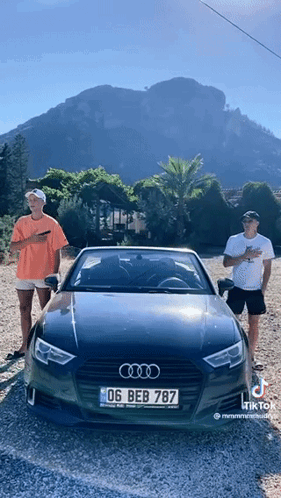 Two Men Standing Next To An Audi With A License Plate That Reads 06 Beb 787 GIF